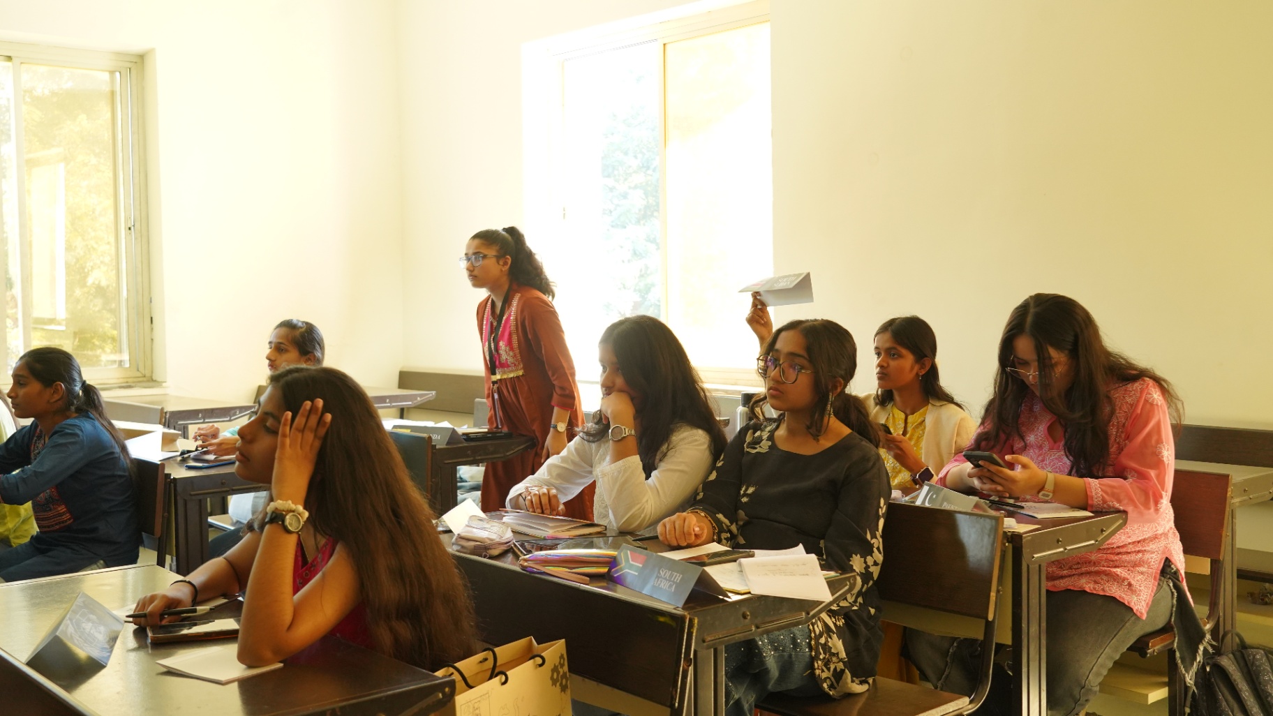 TMF delegates seated by sunlit windows during a daytime committee session.