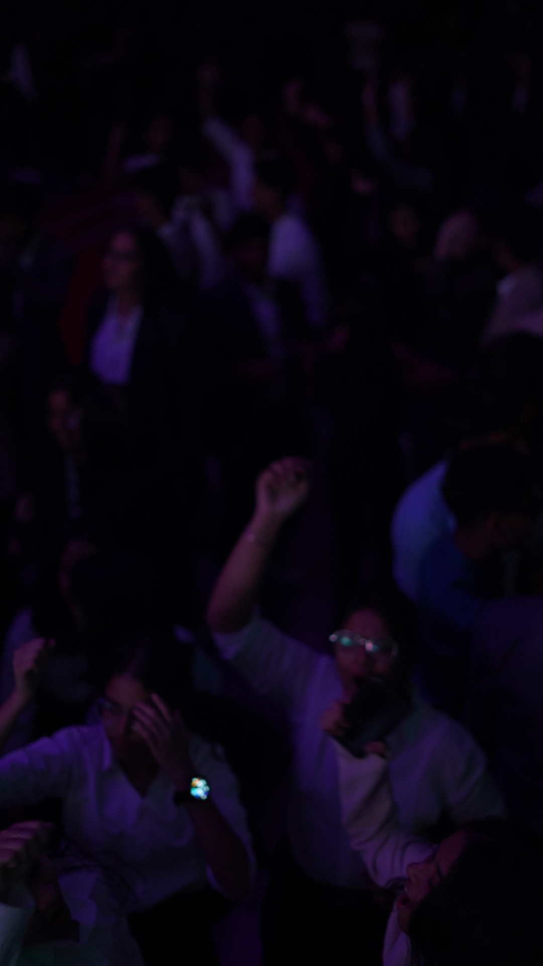 A moody violet-lit TMF crowd scene captured in cinematic soft focus.