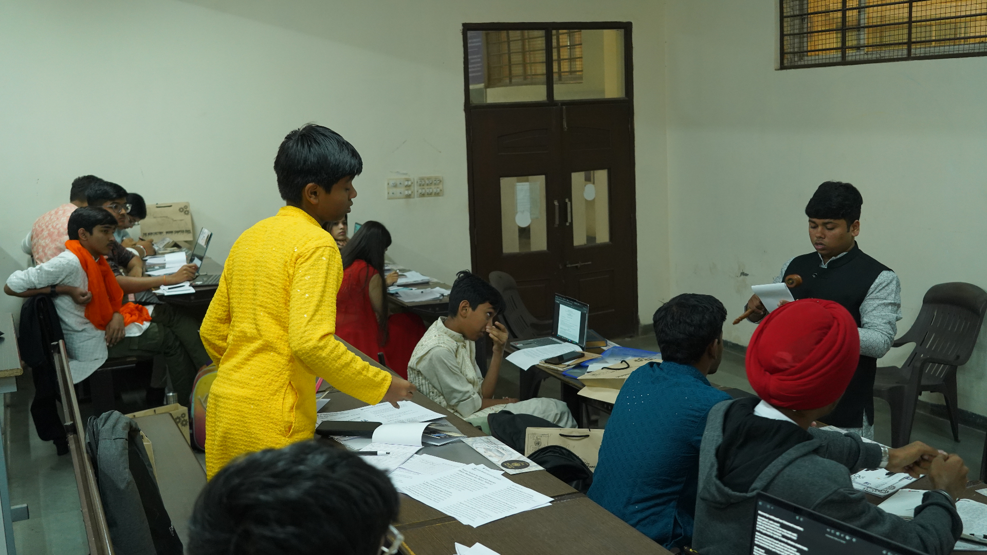 Young TMF delegates standing and debating in a live committee room discussion.